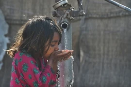 Em nhỏ uống nước từ vòi nước công cộng ở Lahore, Pakistan. (Ảnh: AFP/TTXVN)