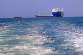 Tàu chở hàng (phải), bị lực lượng Houthi bắt giữ, trên đường về cảng tỉnh Hodeida (Yemen), ngoài khơi Biển Đỏ, ngày 22/11/2023. (Ảnh: AFP/TTXVN)