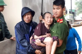 Lực lượng công an huyện Con Cuông giúp dân chuyển đến nơi an toàn. (Ảnh: Bá Hậu/TTXVN)