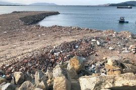 Hàng ngàn khối đất đá, xà bần đổ xuống lấp đầm Thị Nại. (Ảnh: Hà Linh/TTXVN)