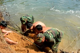 Lực lượng công binh thuộc Bộ Chỉ huy Quân sự tỉnh Phú Yên di chuyển quả bom từ bờ sông lên bờ để xử lý hủy nổ. (Ảnh: Thế Lập/TTXVN)