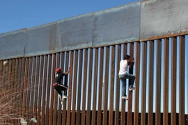 Hai cậu bé cố gắng trèo qua bức tường biên giới giữa Mỹ và Mexico tại Ciudad Juarez, Mexico ngày 26/1. (Nguồn: AFP/TTXVN)