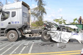 Một phần chiếc xe khách bị vỡ vụn còn mắc trên thân xe container. (Ảnh: Nam Thái/TTXVN)