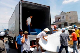 Nhân viên Công ty Kwong Lung - Meko di dời tài sản còn sót lại sau vụ cháy. (Ảnh: Thanh Liêm/TTXVN)