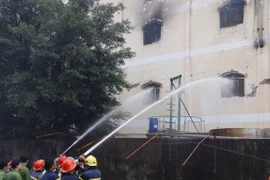 Lực lượng cứu hỏa phun nước dập tắt đám cháy trong nhà xưởng. (Ảnh: Thanh Liêm/TTXVN)