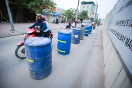 Những chiếc thùng phuy được làm thành dải phân cách giúp người đi đường 'dễ dàng' đi lại, nhất là vào giờ cao điểm. (Ảnh: Minh Sơn/Vietnam+)