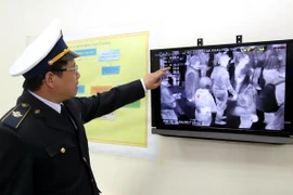 Cán bộ kiểm dịch Y tế cửa khẩu Hữu Nghị kiểm tra thân nhiệt của khách nhập cảnh qua màn hình của máy đo thân nhiệt. (Ảnh: Thái Thuần/TTXVN)