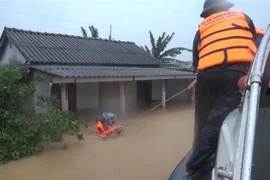 Bộ đội Biên phòng tỉnh Quảng Trị di dời những người dân bị mắc kẹt trong lũ đến nơi an toàn. (Ảnh: Hồ Cầu/TTXVN)