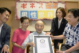 Cụ Yasutaro Koide (giữa) nhận giấy chứng nhận Kỷ lục Thế giới Guinness cụ ông cao tuổi nhất thế giới tại Nagoya ngày 21/8 vừa qua. (Ảnh: Kyodo/TTXVN)