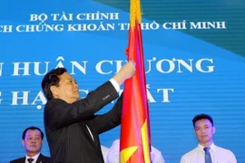 Thủ tướng Nguyễn Tấn Dũng gắn Huân chương Lao động hạng Nhất lên lá cờ truyền thống cho Sở Giao dịch Chứng khoán TP.HCM. (Ảnh: Thanh Vũ/TTXVN)