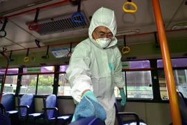 Nhân viên y tế Hàn Quốc khử trùng xe buýt tại thủ đô Seoul ngày 15/6 để ngăn chặn sự lây lan của MERS. (Ảnh: AFP/TTXVN) 