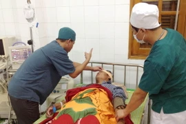 Các y bác sỹ Bệnh viện Đa khoa huyện đảo Bạch Long Vỹ điều trị cho ngư dân Nguyễn Văn Thịnh bị tai nạn do cơn bão số 1. (Ảnh: Nguyễn Đức Quân/TTXVN)