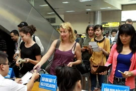 Kiểm tra tờ khai y tế của khách nhập cảnh. (Ảnh: Dương Ngọc/TTXVN)