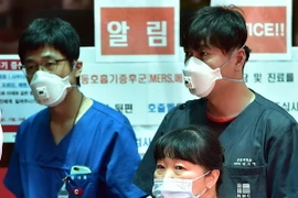 Nhân viên y tế Hàn Quốc bên các tấm biển cảnh báo về MERS tại trung tâm y tế quốc gia. (Ảnh: AFP/TTXVN)