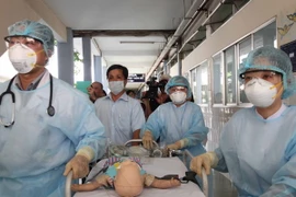 Diễn tập tình huống tiếp nhận bệnh nhi, sau đó chuyển theo lối đi riêng đến phòng cách ly của khoa Nhiễm. (Ảnh: Phương Vy/TTXVN)