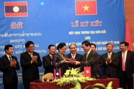 Bộ trưởng Bộ Công Thương Việt Nam Vũ Huy Hoàng và Bộ trưởng Bộ Công Thương Lào Khemmani Pholsena ký Hiệp định. (Ảnh: Tá Chuyên/TTXVN)