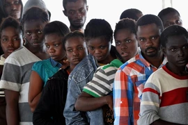 Người di cư xếp hàng nhận đồ ăn trên tàu Hải quân Đức sau khi được cứu vớt trên biển Địa Trung Hải ngày 27/9. (Ảnh: AFP/TTXVN)