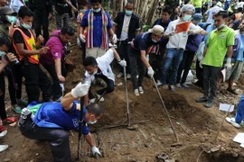 Lực lượng chức năng khai quật thi thể các nạn nhân trong ngôi mộ tập thể tại Thái Lan. (Nguồn: AFP/TTXVN)