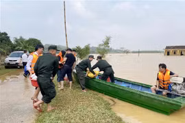 Cán bộ, chiến sỹ của thuộc Tiểu đoàn 2, Trung đoàn Cảnh sát Cơ động Bắc Trung Bộ vận chuyển lương thực, thực phẩm lên thuyền để chuyển vào vùng ngập, đầu tháng 11/2023. (Ảnh: Hữu Quyết/TTXVN)