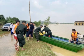 Cán bộ, chiến sỹ của thuộc Tiểu đoàn 2, Trung đoàn Cảnh sát Cơ động Bắc Trung Bộ vận chuyển lương thực, thực phẩm lên thuyền để chuyển vào vùng ngập, đầu tháng 11/2023. (Ảnh: Hữu Quyết/TTXVN)