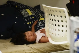 Một em say ngủ tại một cửa hiệu ở Hàng Châu, tỉnh Chiết Giang, Trung Quốc. (Nguồn: AFP/TTXVN)