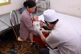 Khám cho trẻ bị mắc sùi mào gà do trước đây từng cắt bao quy đầu tạo cơ sở của bà Hoàng Thị Hiền. (Ảnh: Phạm Kiên/TTXVN)
