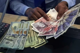Đồng bảng Anh (phải) và đồng USD tại một cửa hàng ngoại hối ở London (Anh). (Nguồn: AFP/TTXVN)