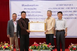 Tham tán Công sứ Đại sứ quán Việt Nam tại Lào Nguyễn Thanh Tùng (phải) trao quà tặng của Tổng Bí thư, Chủ tịch nước Việt Nam Nguyễn Phú Trọng cho lãnh đạo nhà trường. (Nguồn: Xuân Tú/TTXVN)