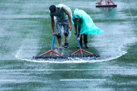 Các nhân viên tại sân đang cố gắng đẩy nước ra ngoài. (Nguồn: TTXVN)