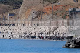Người di cư chạy về phía hàng rào ngăn cách Maroc với Tây Ban Nha, sau khi hàng nghìn người di cư bơi qua biên giới, ở Ceuta (Tây Ban Nha), ngày 19/5/2021. (Nguồn: Reuters/Ảnh chụp màn hình)
