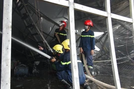 Lực lượng phòng cháy chữa cháy nỗ lực phun nước dập lửa. (Ảnh: Đậu Tất Thành/TTXVN)