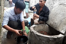 Lực lượng chức năng lấy mẫu nước mang đi thử nghiệm. (Ảnh: Nguyễn Hoàng/TTXVN)