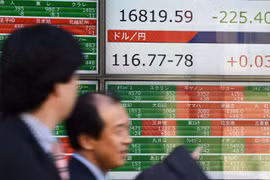 Người dân đi qua bảng thông báo chỉ số chứng khoán ở sàn giao dịch Tokyo. (Nguồn: AFP)
