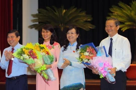 Ông Lê Văn Khoa và bà Nguyễn Thị Thu, tân Phó chủ tịch Ủy ban Nhân dân Thành phố Hồ Chí Minh nhận hoa chúc mừng của lãnh đạo thành phố. (Ảnh: Hoàng Hải/TTXVN)