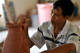 Người thợ gốm Phù Lãng tạo hoa văn cho sản phẩm. (Ảnh: Thanh Hà/TTXVN)