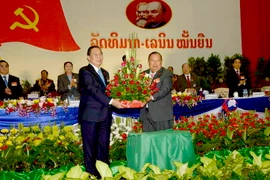 Tổng Bí thư Đảng Nhân dân cách mạng Lào khóa IX Choummaly Sayasone (trái) tặng hoa chúc mừng Tổng Bí thư khóa X Bounnhang Vorachith (phải). (Ảnh: Phạm Kiên/Vietnam+)