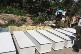 Lực lượng chức năng khẩn trương làm các thủ tục để chuyển thi thể các nạn nhân khỏi hiện trường. (Ảnh: Nguyễn Chiến/Vietnam+)