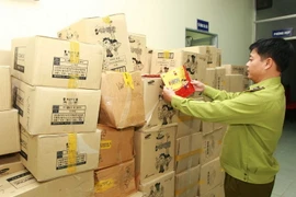  Lực lượng chức năng kiểm tra các sản phẩm nghi nhập lậu vừa bị bắt giữ. (Ảnh: Doãn Tấn/TTXVN)