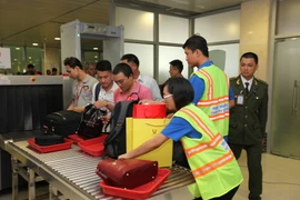 Thanh niên tình nguyện giúp đỡ hành khách tại khu vực máy soi kiểm tra an ninh ở sân bay Tân Sơn Nhất. (Ảnh: Mạnh Linh/TTXVN)