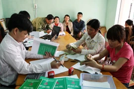 Các hộ gia đình nghèo làm việc với cán bộ Ngân hàng. (Nguồn: TTXVN)