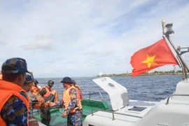 Tàu 471 tiến hành thủ tục bàn giao ngư dân Phan Kiệt cho đảo Song Tử Tây để đưa lên bờ điều trị. (Ảnh: TTXVN phát)