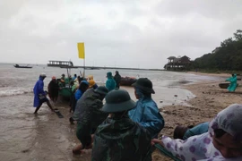 Cán bộ, chiến sỹ Đồn biên phòng Cửa Đại (Hội An) giúp ngư dân đưa phương tiện loại nhỏ đến nơi trú tránh an toàn. (Ảnh: Đoàn Hữu Trung/TTXVN)