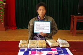 Đối tượng Xôm Bích cùng tang vật vụ án. (Ảnh: TTXVN phát)