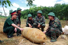 Lực lượng chức năng khảo sát, lên phương án hủy nổ quả bom. (Ảnh: TTXVN phát)