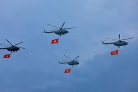 Máy bay trực thăng mang cờ Đảng, cờ Tổ quốc bay qua Lễ đài. (Ảnh: Dương Giang/TTXVN)