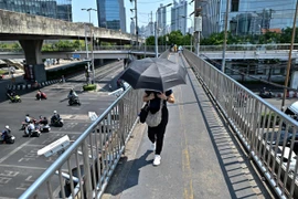 Người dân di chuyển dưới trời nắng gắt tại Bangkok, Thái Lan ngày 25/4/2024. (Ảnh: AFP/TTXVN)