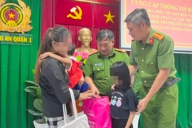 Lực lượng Công an Thành phố Hồ Chí Minh trao trả hai cháu bé về với gia đình chị Nguyễn Thị Chi. (Ảnh: TTXVN phát)