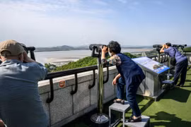 Khách du lịch quan sát bằng ống nhòm Khu phi quân sự (DMZ) liên Triều từ Đài quan sát Odusan ở Paju, Hàn Quốc, ngày 12/5/2022. (Ảnh: AFP/TTXVN)