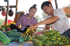 Không khí sum vầy của ngày Tết trong dịp gói bánh tét. (Ảnh: Nguyễn Hằng/TTXVN)