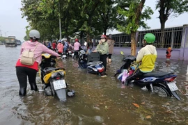 Trận mưa lớn khiến Khu công nghiệp Giao Long (huyện Châu Thành, Bến Tre) bị ngập nặng, công nhân phải lội bì bõm trong biển nước vào sáng 21/5. (Ảnh: Chương Đài/TTXVN)